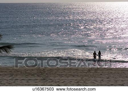Stock Image - Two people in the ocean at twilight. Fotosearch