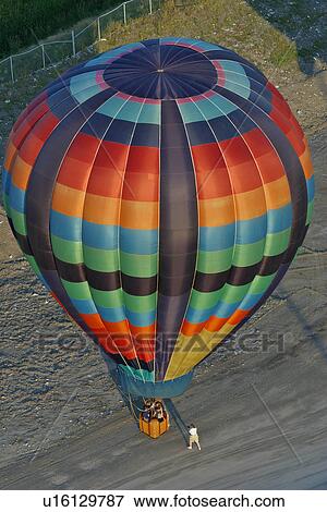 Aerial view of multicoloured hot air balloon landing on ground, with person on road taking photo View Large Photo Image Stock Photo - Aerial view of multicoloured hot air balloon landing on ground, with person on road taking photo. Fotosearch