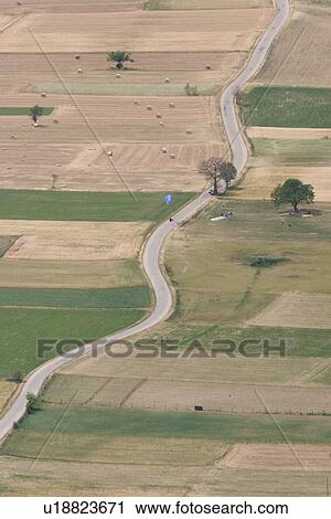 Aerial view of plain outside Norcia, with pattern created by cultivated green and brown fields, winding road and paragliders landing View Large Photo Image Stock Image - Aerial view of plain outside Norcia, with pattern created by cultivated green and brown fields, winding road and paragliders landing. Fotosearch