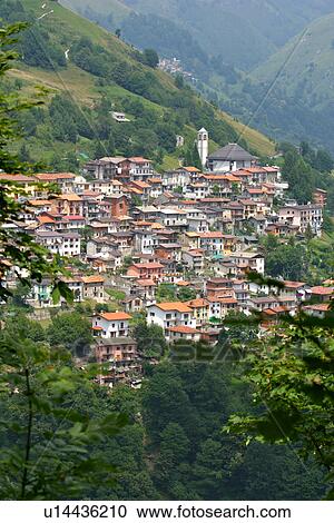 Aerial view of village nestling in mountains around Lake Como, framed by green trees in foreground, and slopes of hills and mountains behind View Large Photo Image Stock Image - Aerial view of village nestling in mountains around Lake Como, framed by green trees in foreground, and slopes of hills and mountains behind. Fotosearch