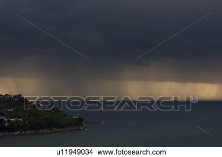 Picture - Agropoli lighthouse and harbour in approaching storm at dusk. Fotosearch
