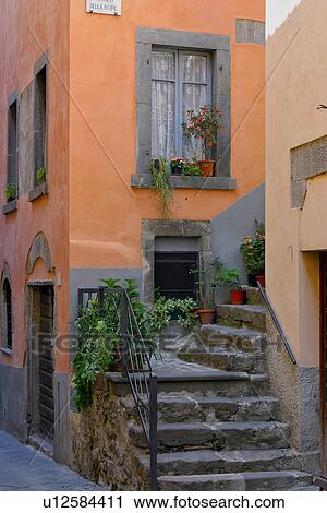 Stock Image - Architectural detail of stairway, peach -coloured walls, with stone window frames, Italian street. Fotosearch