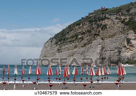 Stock Photo - Beach at Meta, Campania, Southern Italy, with red and white umbrellas and white picket fence. Fotosearch