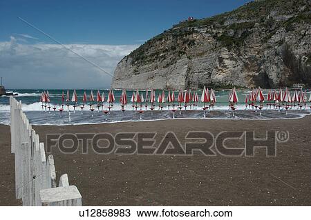 Stock Image - Beach at Meta, Campania, with red and white umbrellas, and white picket fence. Fotosearch