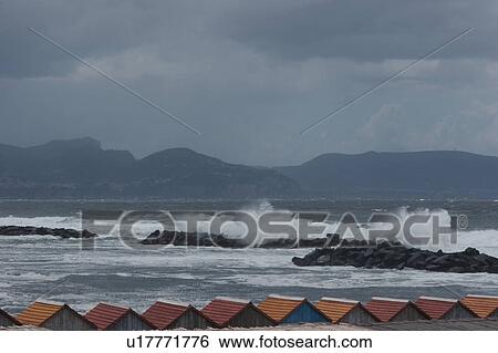 Beach near Meta, Southern Italy, with row of red and orange beach hut roofs in foreground, sea, surf, and mountains on distant shore View Large Photo Image Stock Photograph - Beach near Meta, Southern Italy, with row of red and orange beach hut roofs in foreground, sea, surf, and mountains on distant shore. Fotosearch
