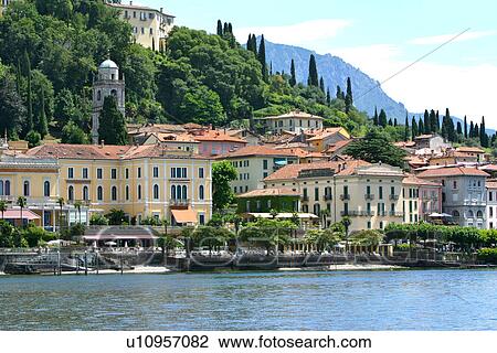 Stock Image - Bellagio, view of harbour and town from water, church bell tower and mountain slope in background, on sunny summer afternoon. Fotosearch