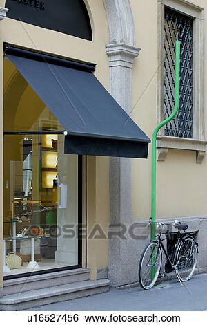 Bike attached to green pipe in front of Steiger shop in Milan fashion district View Large Photo Image Stock Photograph - Bike attached to green pipe in front of Steiger shop in Milan fashion district. Fotosearch