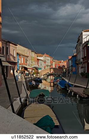 Boats moored along Burano canal in sunlight before an evening summer storm, View Large Photo Image Stock Image - Boats moored along Burano canal in sunlight before an evening summer storm, . Fotosearch
