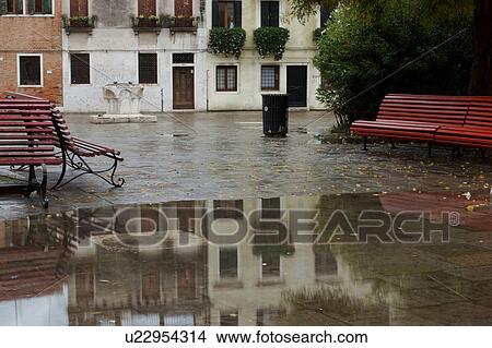 Picture - Campo after rain with reflection of red bench and buildings. Fotosearch