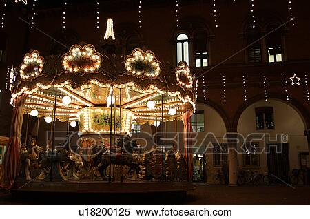 Stock Photography - Carousel with horses, Christmas lights at night in Ferrara Piazza. Fotosearch