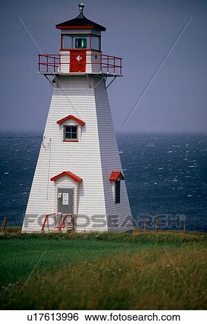 Stock Photograph - Cliff lighthouse against sky, with sea beyond. Fotosearch