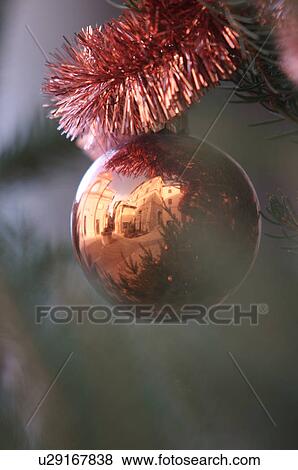 Closeup of orange Christmas ornament and tinsel on evergreen tree with reflection of piazza, church and medieval buildings in Italian village View Large Photo Image Stock Photo - Closeup of orange Christmas ornament and tinsel on evergreen tree with reflection of piazza, church and medieval buildings in Italian village. Fotosearch