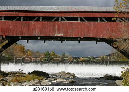 Stock Photo - Covered bridge, Taft Bridge, Vermont USA, with view of waterfall and river, grey storm sky . Fotosearch