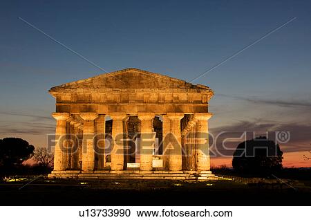 Stock Image - Cyclist in early morning light, from under arched portico, front of Cattedrale (Loggia del Mercato) on cobble stone street, with Campanile. Fotosearch