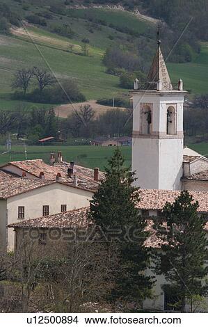 Detail aerial view of white church bell tower of Norcia, surrounding buildings and green fields beyond on sunny spring day View Large Photo Image Picture - Detail aerial view of white church bell tower of Norcia, surrounding buildings and green fields beyond on sunny spring day. Fotosearch