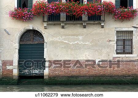 Stock Photo - detail of arch doorway 'garage" on canal, with balcony of red geraniums above. Fotosearch