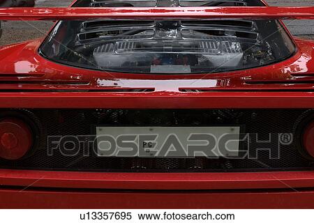 Detail of parked red Ferrari, back view, showing engine through transparent panel, on cloudy rainy day Stock Photography