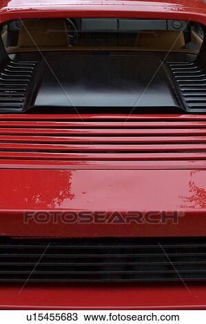 Stock Image - Detail of parked red Ferrari, rear view, on cloudy rainy day. Fotosearch