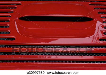 Stock Image - Detail of parked red Ferrari, rear view, of back deck, on cloudy rainy day. Fotosearch