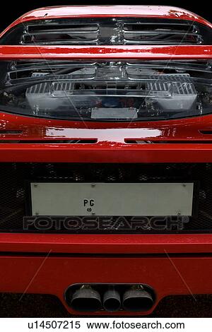 Stock Photography - Detail of parked red Ferrari, rear view, showing engine through tranparent panel, on cloudy rainy day. Fotosearch