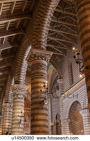 Stock Image - Detail view of side nave of Orvieto Duomo, showing black and white striped columns, arches, wooden sloped ceiling. Fotosearch