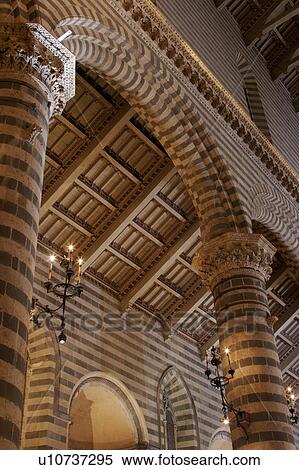 Stock Photography - Detail view of side nave of Orvieto Duomo, showing black and white striped columns, arches, wooden sloped ceiling. Fotosearch