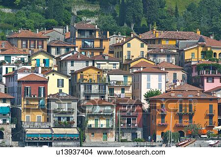 Picture - Detail view of Varenna from lake, showing rows of houses along lake shore, and green hill slopes in background. Fotosearch