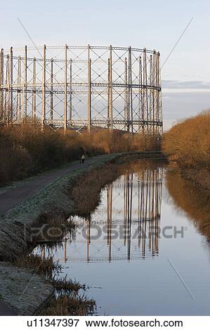 Stock Photo - Empty oil or gas storage tanks in Glasgow Scotland, with circular girder frame reflected in river, on early frosty morning . Fotosearch