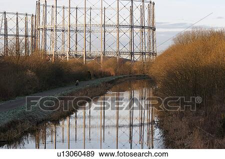 Stock Photo - Empty oil or gas storage tanks in Glasgow Scotland, with circular girder frame reflected in river, on early frosty morning . Fotosearch