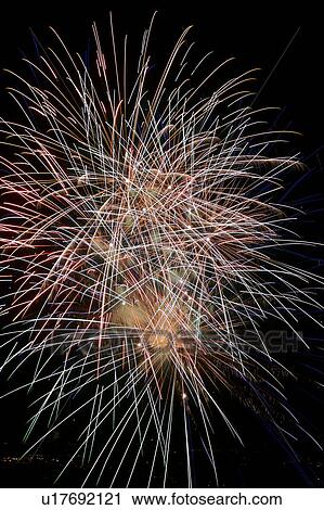 Stock Image - Fireworks exploding in the black night sky. Fotosearch