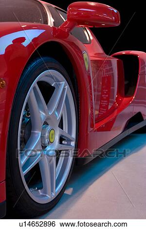 Stock Photograph - Front quarter detail of new red Ferrari sportscar showing front wheel, side mirror and rear air intake. Fotosearch