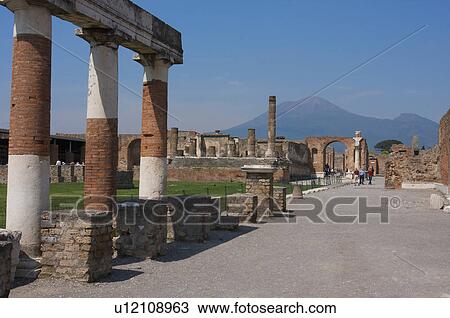 Stock Image - In the shadow of Vesuvius, the ruins of Pompei - Forum, with Vesuvius seen through Arch. Fotosearch