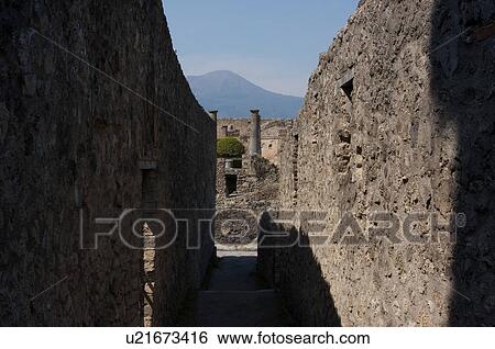 Stock Photograph - In the shadow of Vesuvius, the ruins of Pompei - entrance to upper level of Great Theatre with vesuvius in distance. Fotosearch
