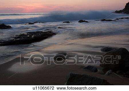 Stock Image - Italian beach at sunset, with motion blur of waves. Fotosearch