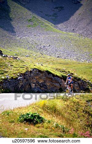Stock Photograph - Lone cyclist travelling up hill on mountain road. Fotosearch