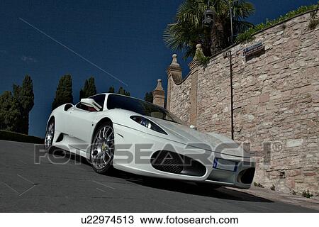 Low front-side view of white Ferrari on road in Assisi, at Mille Miglia, with blue sky and cypress trees in background View Large Photo Image Stock Image - Low front-side view of white Ferrari on road in Assisi, at Mille Miglia, with blue sky and cypress trees in background. Fotosearch