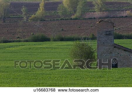 Stock Photo - Old church in ruins in farmers field, in late afternoon light, ploughed brown fields in background. Fotosearch