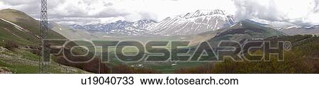 Panorama view of cloudy winter day at Piano Grande with sun on green meadow, and snow on mountains View Large Photo Image Stock Image - Panorama view of cloudy winter day at Piano Grande with sun on green meadow, and snow on mountains. Fotosearch