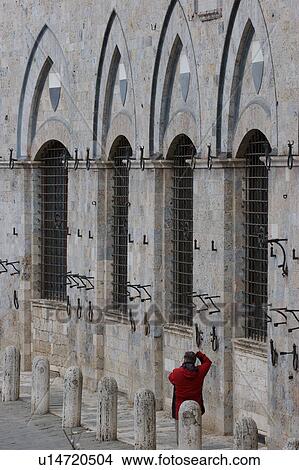 rear view of tourist in red coat, standing beside Palazzo Pubblico in Siena, photographing series of arches and windows of facade View Large Photo Image Picture - rear view of tourist in red coat, standing beside Palazzo Pubblico in Siena, photographing series of arches and windows of facade. Fotosearch
