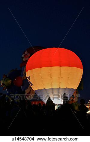 Red white and blue hot air balloon on ground, illuminated from interior, night lights, people silhouetted View Large Photo Image Picture - Red white and blue hot air balloon on ground, illuminated from interior, night lights, people silhouetted. Fotosearch