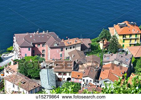 Picture - Rooftop view of town of Castello di Vezio beside blue water of Lake Como in bright morning sunshine. Fotosearch