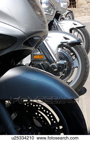 Stock Image - Row of BMW motorbikes showing front wheels, Italian Village Street. Fotosearch