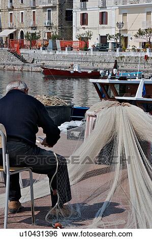 Scario harbour with boats, fisherman repairing nets, small fishing boats moored, and town of Scario beyond, on sunny, summer morning View Large Photo Image Stock Photograph - Scario harbour with boats, fisherman repairing nets, small fishing boats moored, and town of Scario beyond, on sunny, summer morning. Fotosearch