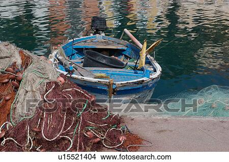 Picture -  Scario harbour with old fishing boat moored, fishing nets on quayside, on sunny, summer morning. Fotosearch