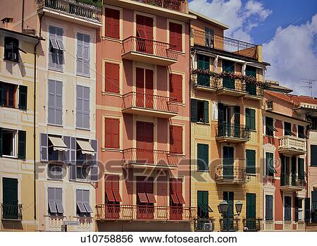 Stock Photograph - Sea front houses, with brightly coloured shuttered windows in afternoon sunlight, Santa Margherita, Italy. Fotosearch