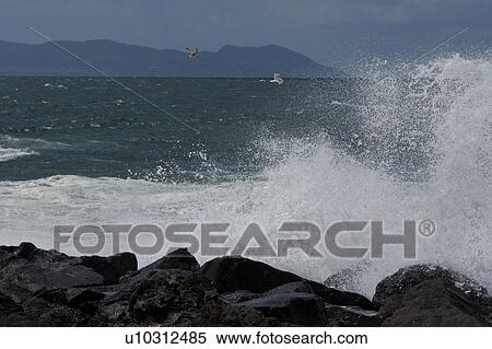 Sea surf breaking on rocks with blue sky, sea, and mountains in distance View Large Photo Image Stock Photography - Sea surf breaking on rocks with blue sky, sea, and mountains in distance. Fotosearch