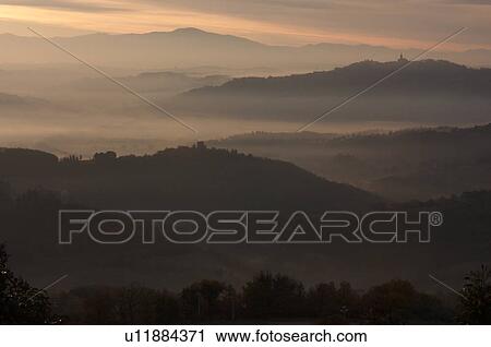 Sunrise over Tiber valley with grey pink and golden sky in the early morning mist of winter, with tree outline in foreground, and hilltop town of Todi in distance View Large Photo Image Stock Image - Sunrise over Tiber valley with grey pink and golden sky in the early morning mist of winter, with tree outline in foreground, and hilltop town of Todi in distance. Fotosearch