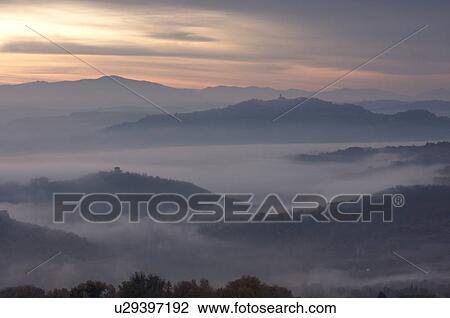 Sunrise over Tiber valley with grey pink and golden sky in the early morning mist of winter, with tree outline in foreground View Large Photo Image Stock Image - Sunrise over Tiber valley with grey pink and golden sky in the early morning mist of winter, with tree outline in foreground. Fotosearch