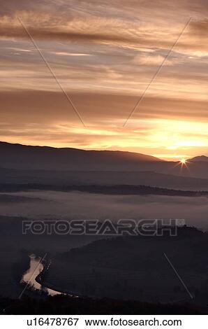 Sunrise over Tiber valley with grey pink and golden sky in the early morning mist of winter, with tree outline in foreground, and River Tiber curving beside hill View Large Photo Image Stock Photo - Sunrise over Tiber valley with grey pink and golden sky in the early morning mist of winter, with tree outline in foreground, and River Tiber curving beside hill. Fotosearch