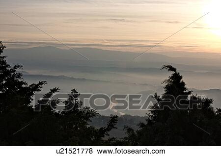 Sunrise over Tiber valley with grey pink and golden sky in the early morning mist of winter, with tree outline in foreground, and River Tiber curving beside hill View Large Photo Image Stock Photo - Sunrise over Tiber valley with grey pink and golden sky in the early morning mist of winter, with tree outline in foreground, and River Tiber curving beside hill. Fotosearch